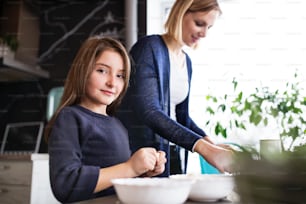 A small girl with her mother at home, cooking. Family and generations concept.