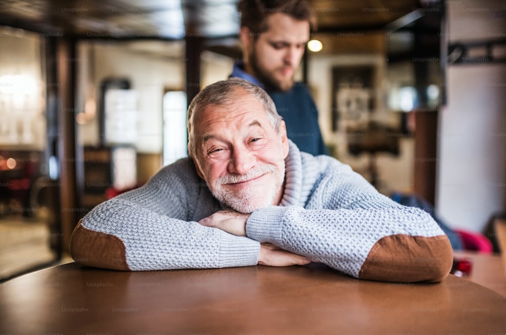 Padre anziano felice e il suo giovane figlio in un pub.
