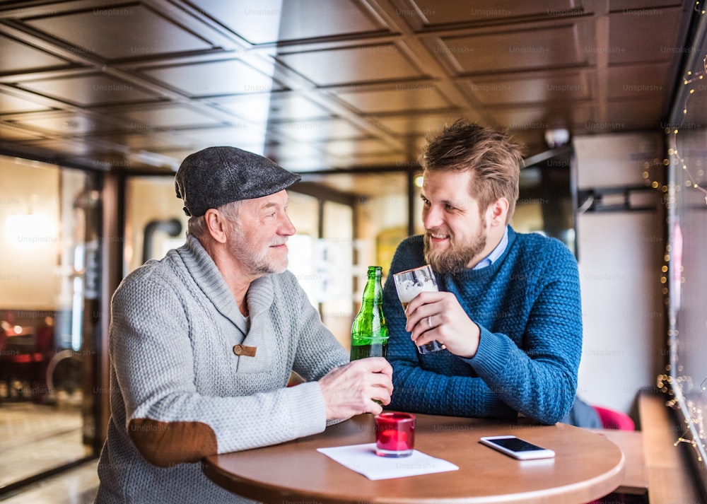 Padre mayor y su hijo pequeño bebiendo cerveza en un pub.