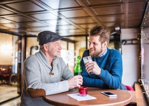 Senior father and his young son drinking beer in a pub.