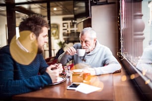 Senior father and his young son drinking coffee in a cafe.