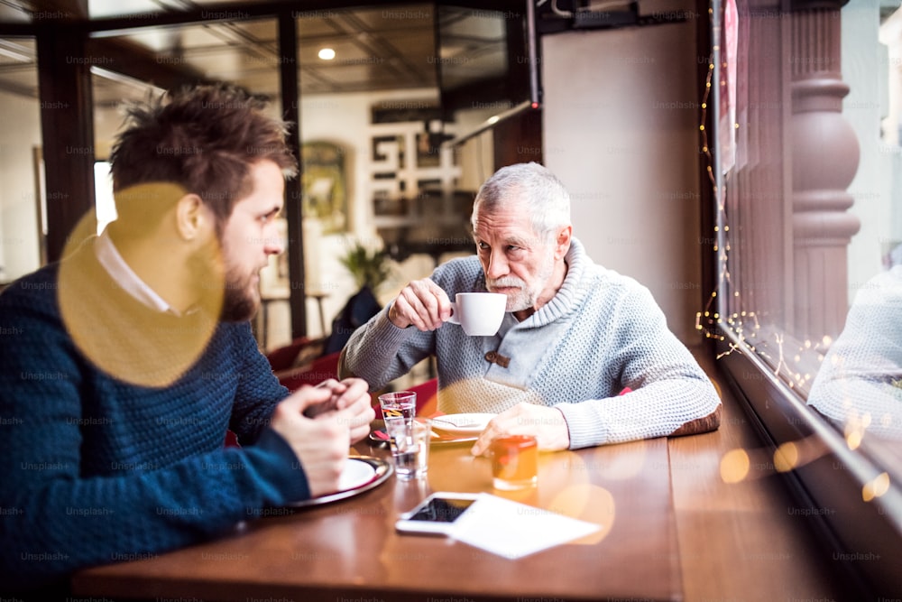 Il padre anziano e il suo giovane figlio bevono caffè in un bar.