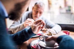 Senior father and his young son drinking coffee in a cafe.