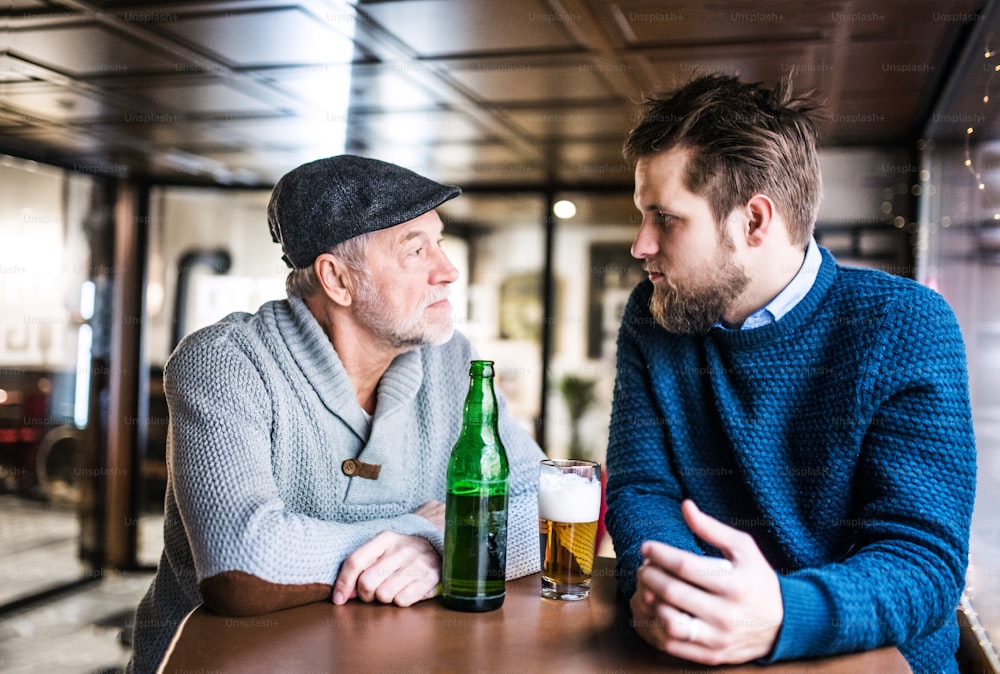 Un père âgé et son jeune fils buvant de la bière dans un pub.