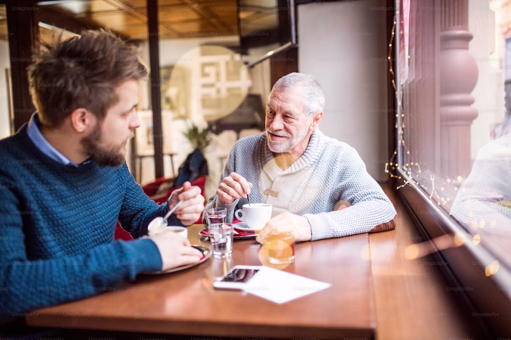 Il padre anziano e il suo giovane figlio bevono caffè in un bar.