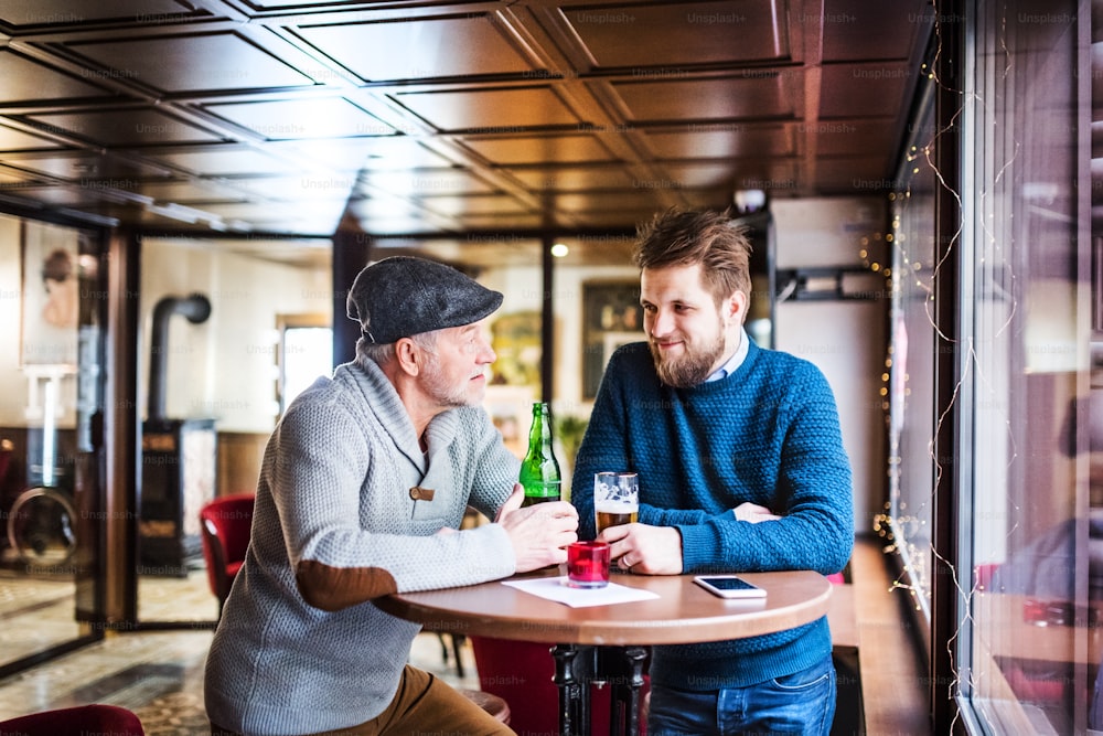 Senior father and his young son drinking beer in a pub.