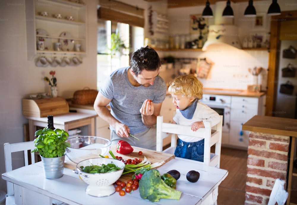 Young father with a toddler boy cooking. A man with his son making vegetable salad.