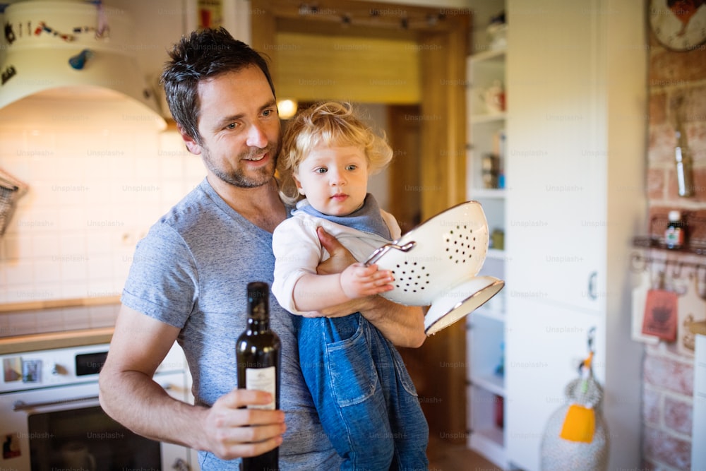 Young father with a toddler boy cooking. A man with his son carrying olive oil.