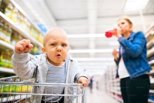 Jovem mãe irreconhecível com seu filhinho no supermercado, fazendo compras.