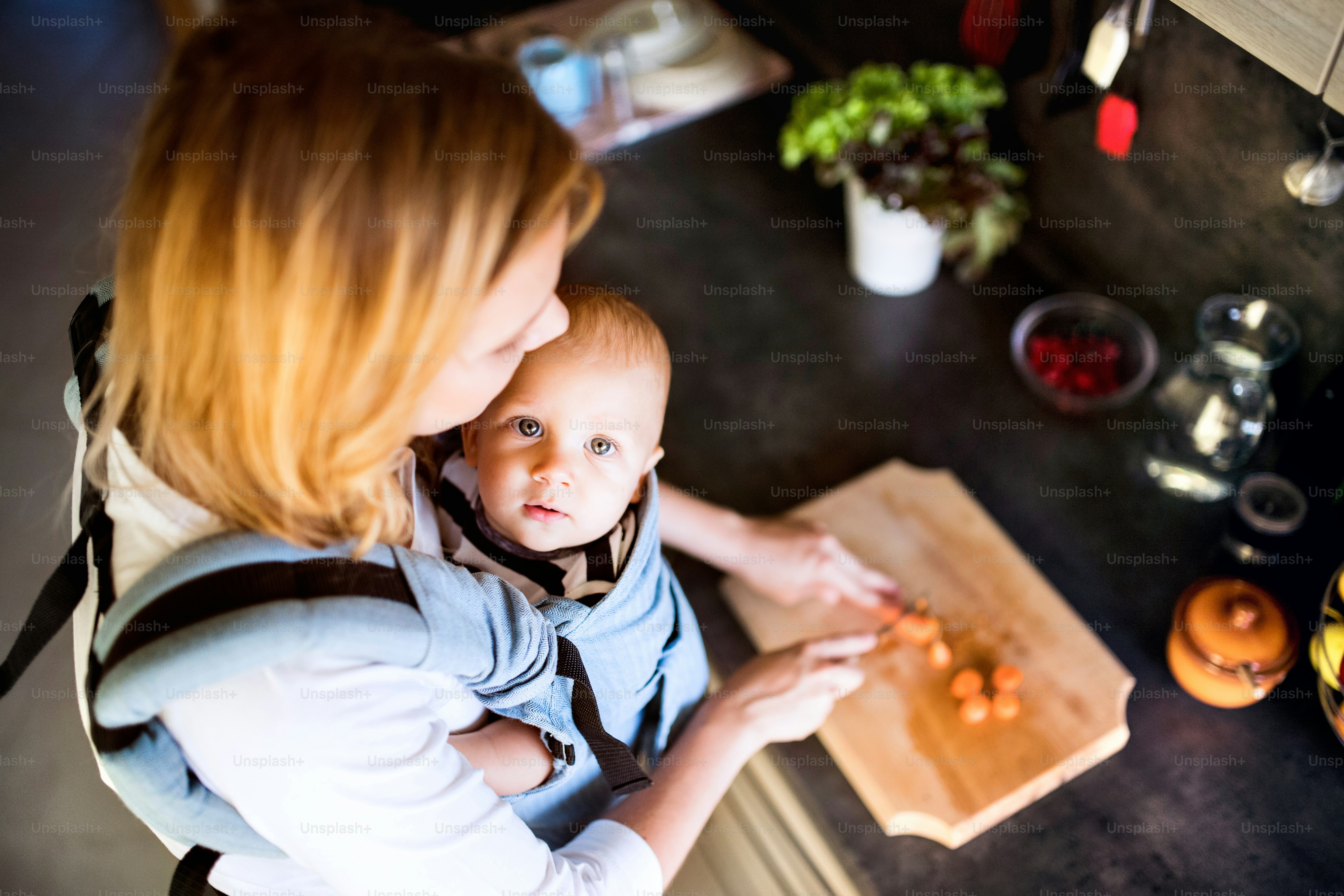 Ibu muda dengan seorang bayi laki-laki yang melakukan pekerjaan rumah. Wanita cantik dan bayi laki-laki di dapur. Tampilan atas.