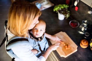 Junge Mutter mit einem kleinen Sohn bei der Hausarbeit. Schöne Frau und kleiner Junge in der Küche. Draufsicht.