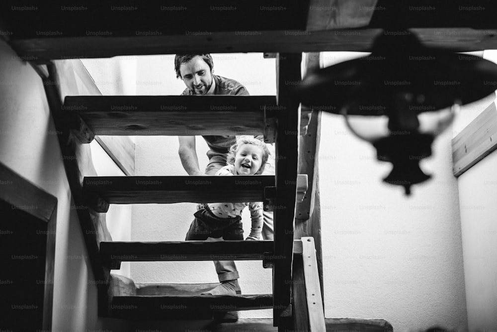 Young father at home with his cute little son walking slowly up the stairs.