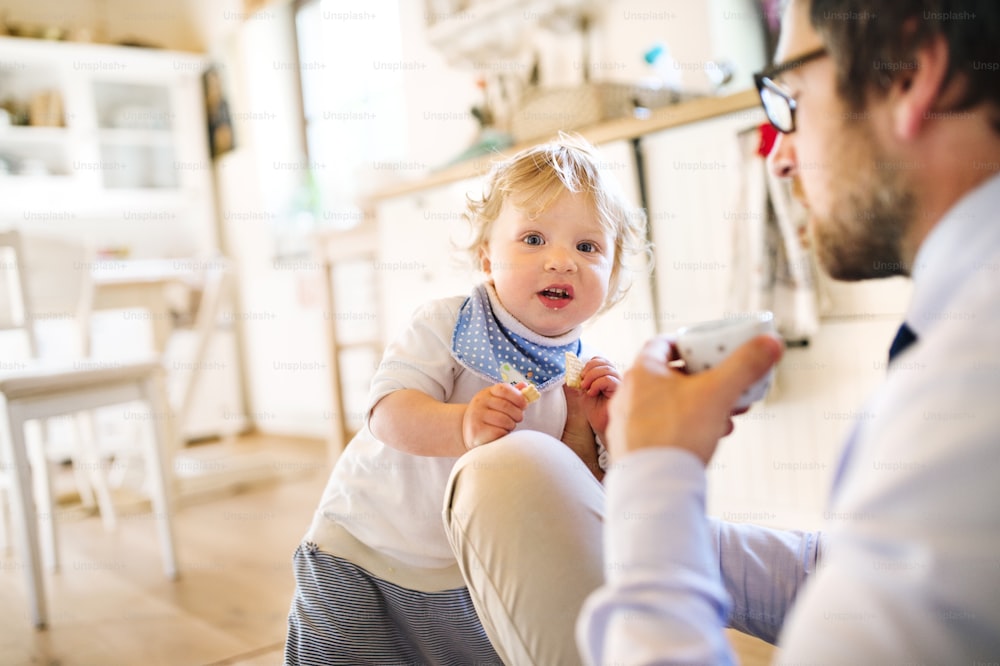 Jeune homme d’affaires rentrant du travail, se reposant, buvant du café, jouant avec son petit fils.