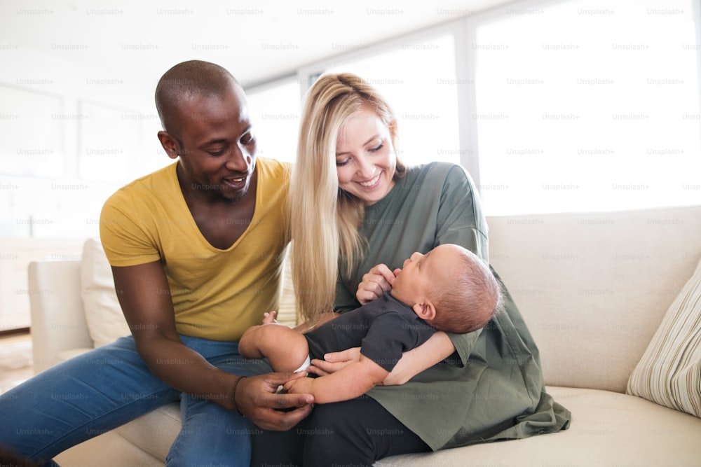 Beautiful young interracial family at home holding their cute little baby son.