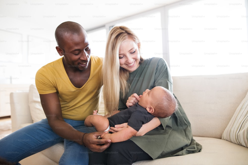 Schöne junge interrassische Familie zu Hause, die ihren süßen kleinen Sohn hält.