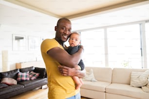 귀여운 아기 아들을 품에 안고 있는 젊은 아프리카계 미국인 아버지