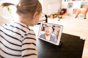 Bambina irriconoscibile a casa con un tablet, video chat con suo padre.