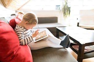 Unrecognizable little girl at home holding a tablet, video chatting with her mother.