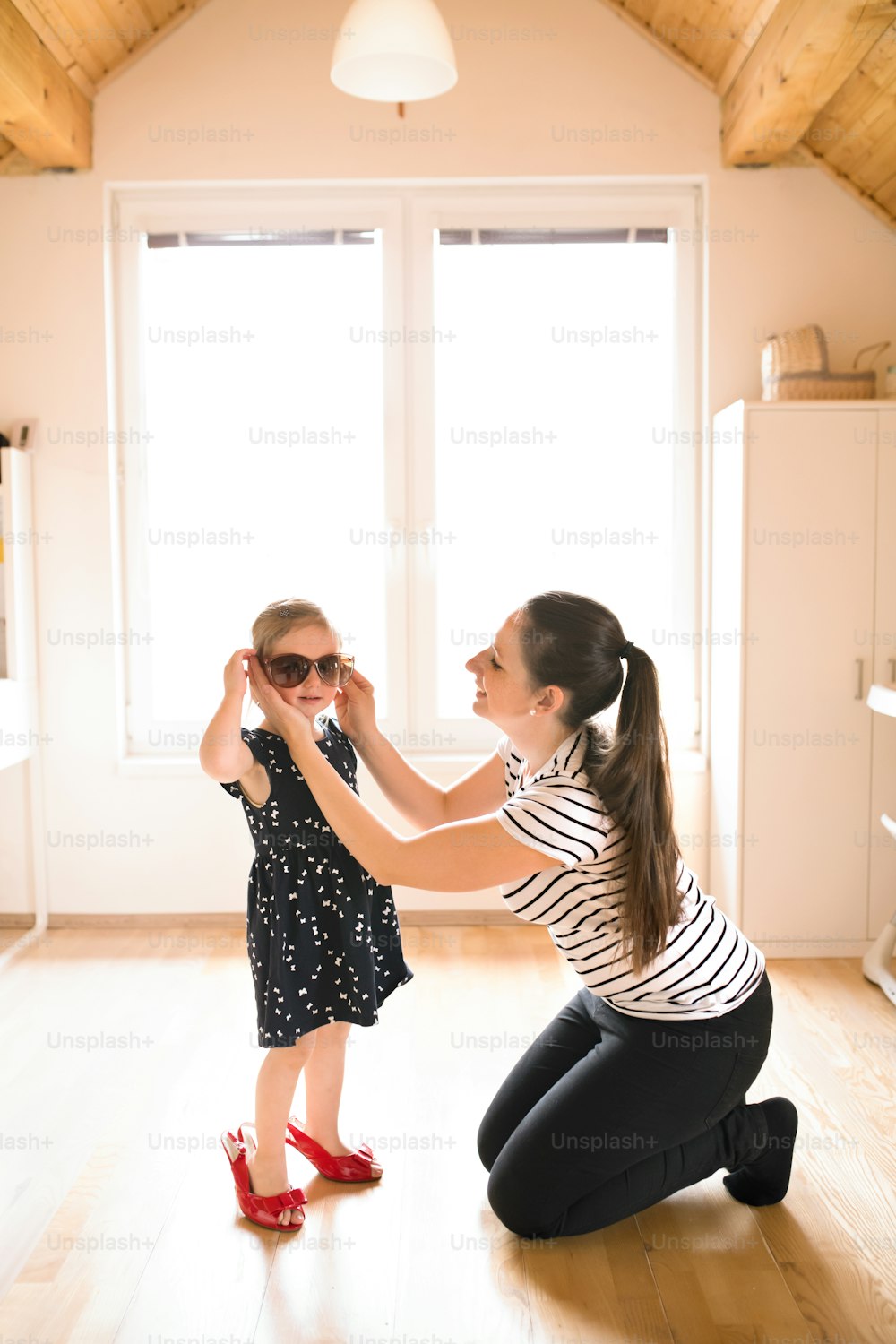 Bella giovane madre mette gli occhiali da sole alla sua graziosa figlioletta.