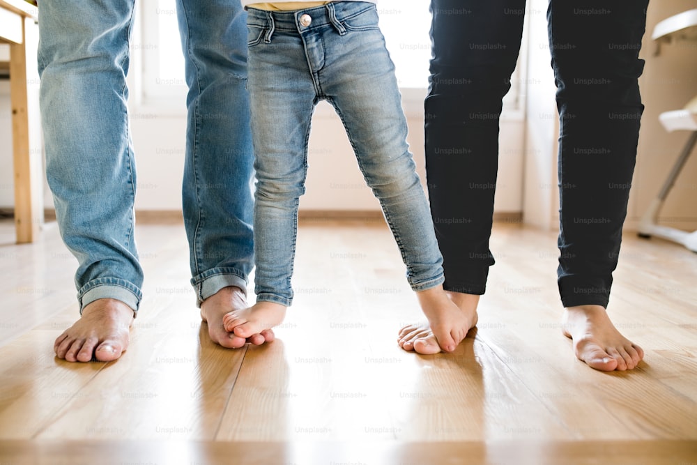 Hermosa familia joven. Primer plano de los pies descalzos de madre, padre e hija.