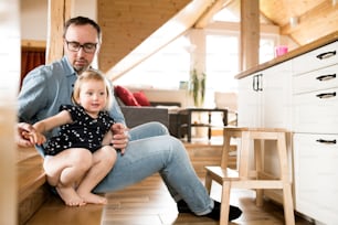 Young father at home with his cute little blonde daughter.