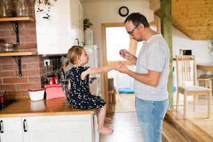 귀여운 딸이 손톱을 칠하는 부엌에서 집에 있는 젊은 아버지.