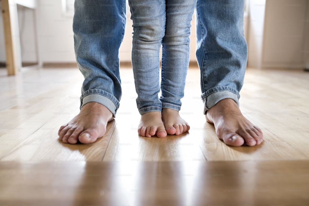 Hermosa familia joven. Primer plano de los pies descalzos de padre e hija.