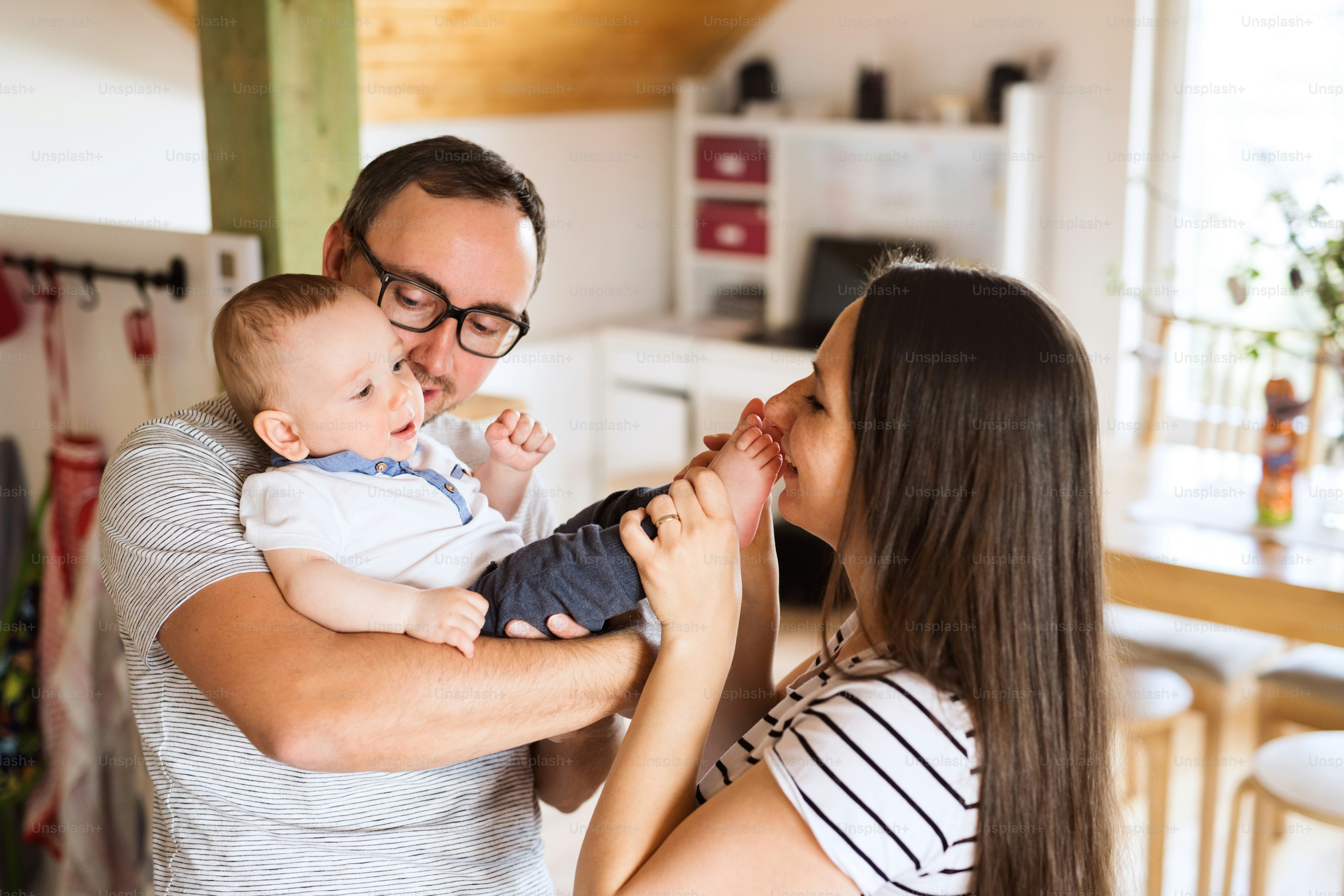 Beautiful young parents at home holding their cute baby son in the arms.