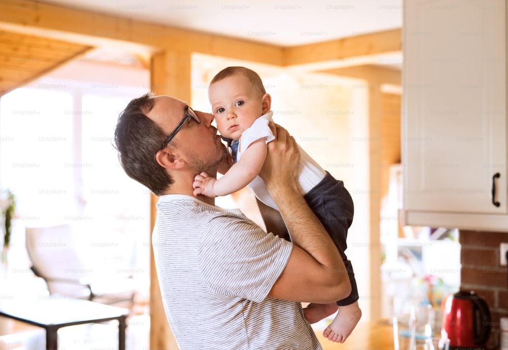 Padre joven en casa sosteniendo a su lindo bebé en sus brazos