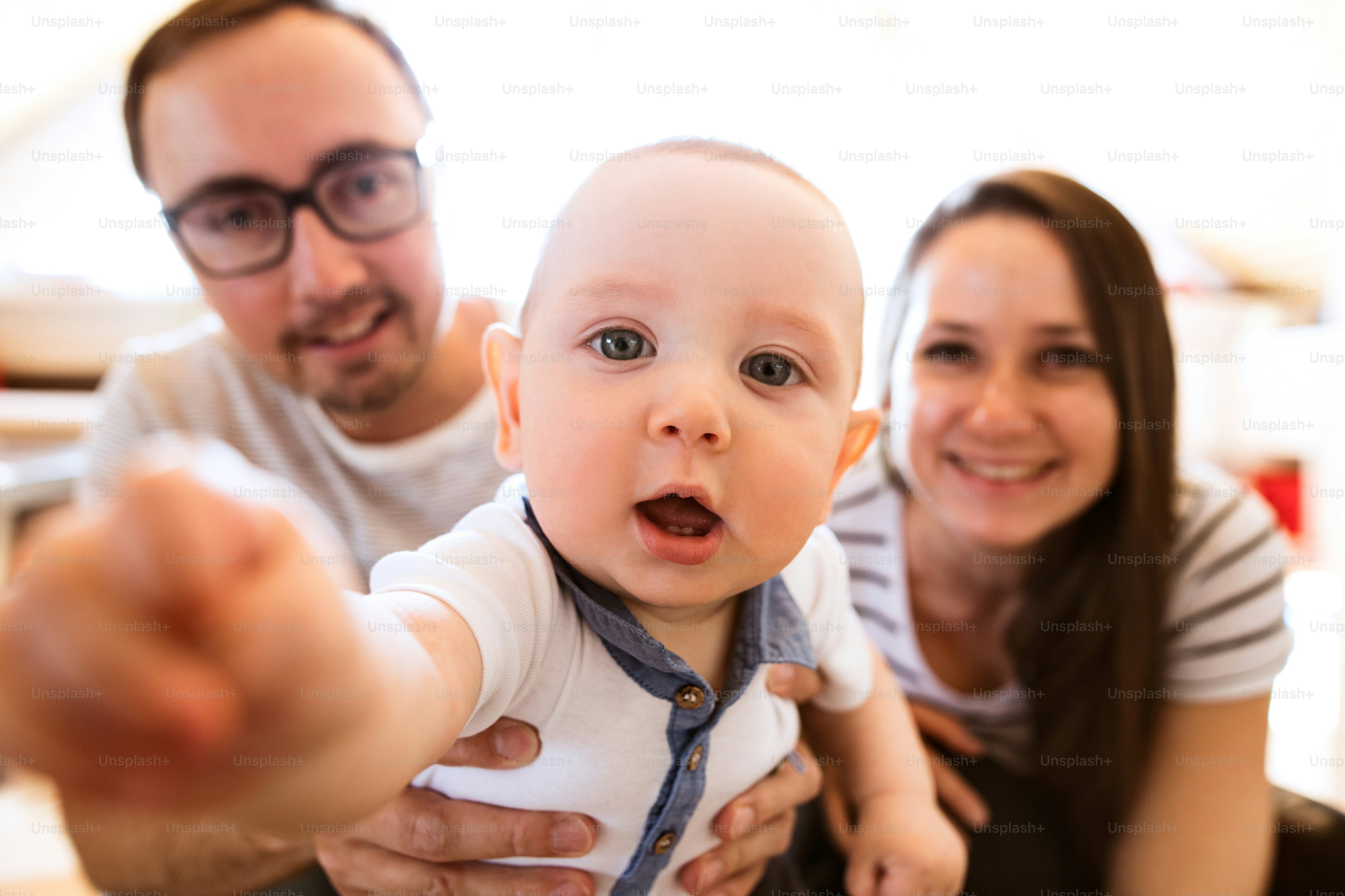 Beautiful young parents at home holding their cute baby son in the arms.