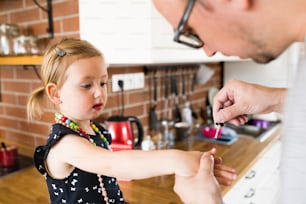 집에서 귀여운 딸과 함께 손톱을 칠하는 젊은 아버지.