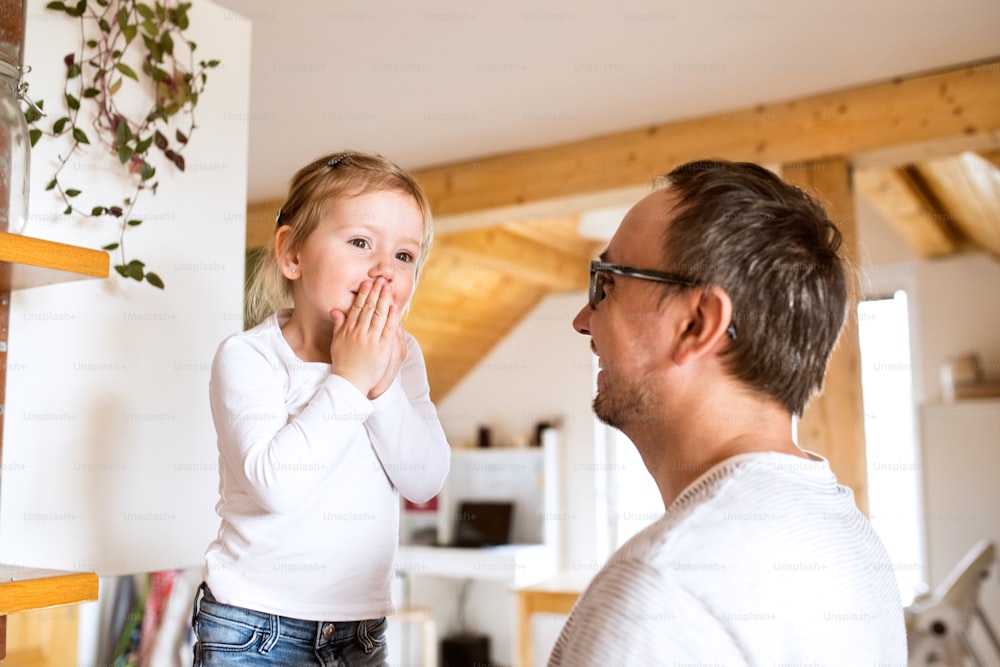 Young father at home with his cute little daughter standing on kitchen countertop.