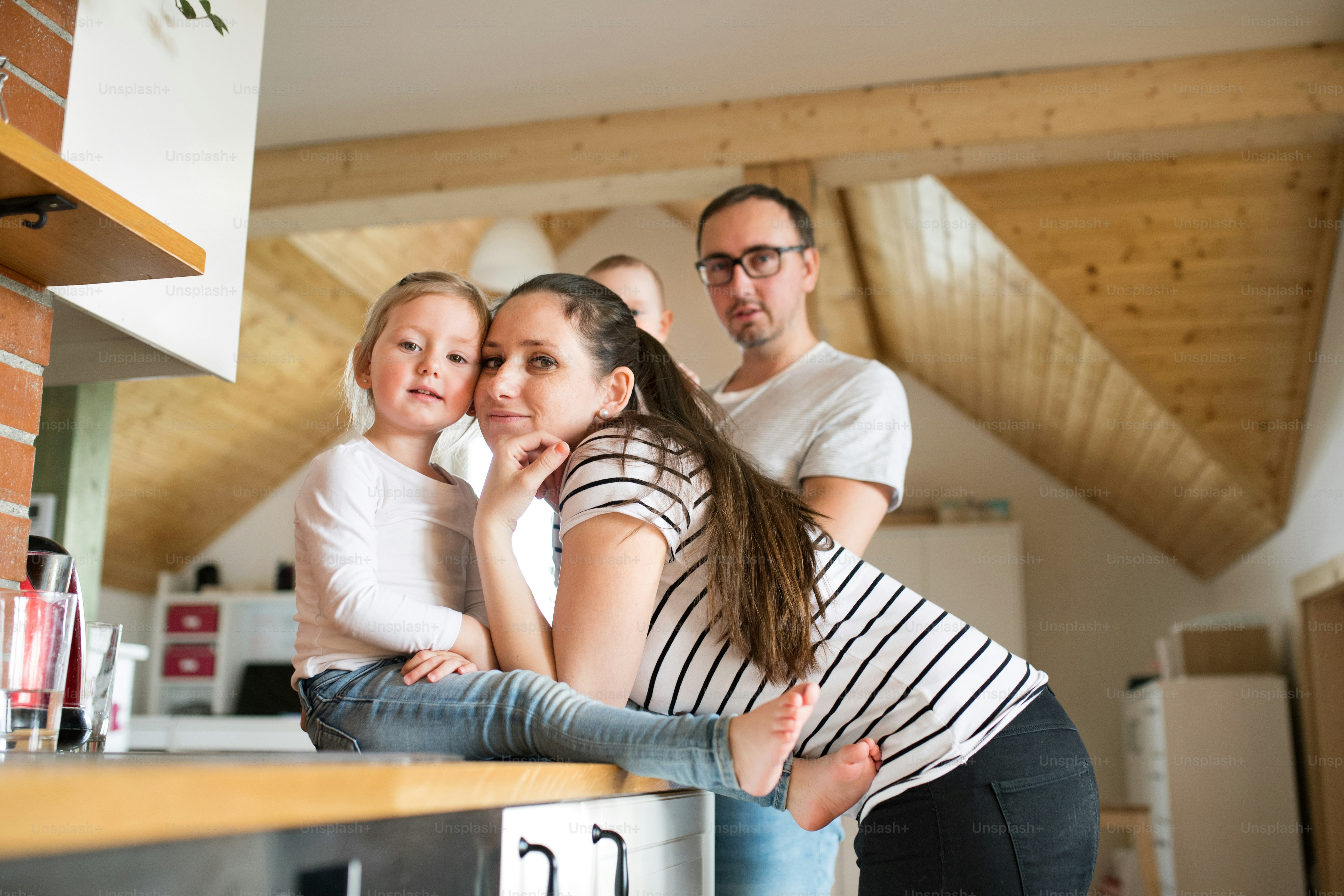 Beautiful young parents at home holding their cute son and daughter in the arms.