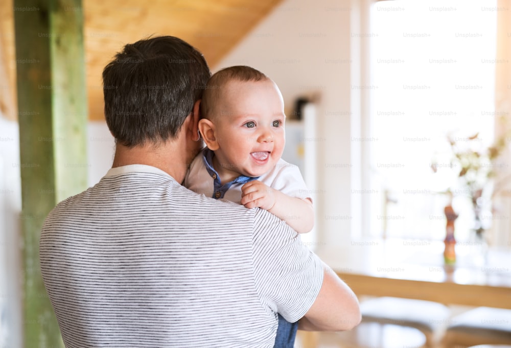 Unrecognizable young father at home holding his cute baby son in his arms