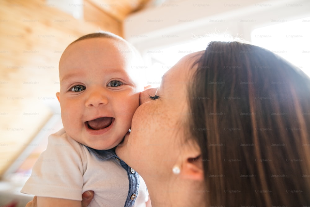 Beautiful mother holding her cute baby son in the arms.