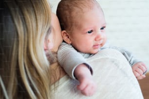 赤ん坊の息子を腕に抱いている認識できない若い母親