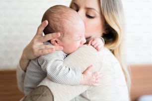 Hermosa joven madre sosteniendo a su bebé en sus brazos
