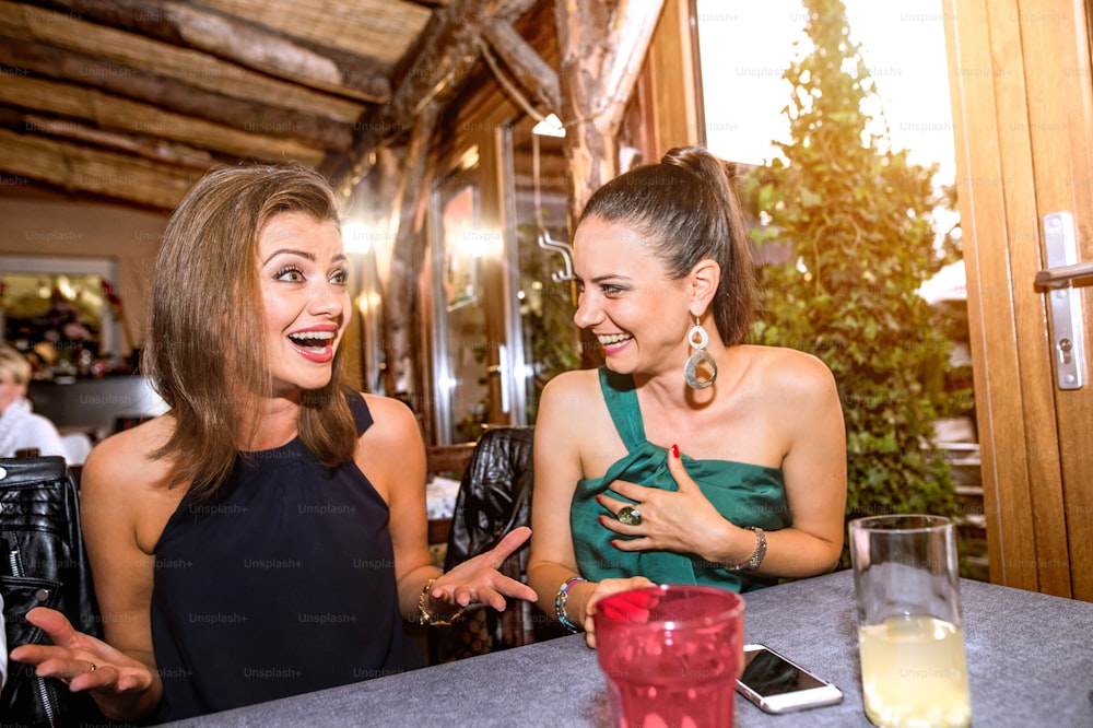 Young beautiful women with cocktails in bar or club talking, having fun