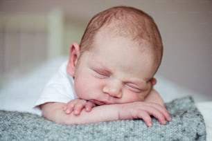 Cute little newborn baby boy lying on bed, sleeping, close up