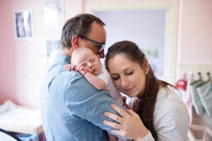 生まれたばかりの赤ん坊の息子を腕に抱く若い父親と母親
