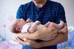 Close up of unrecognizable young father holding his newborn baby son in his arms