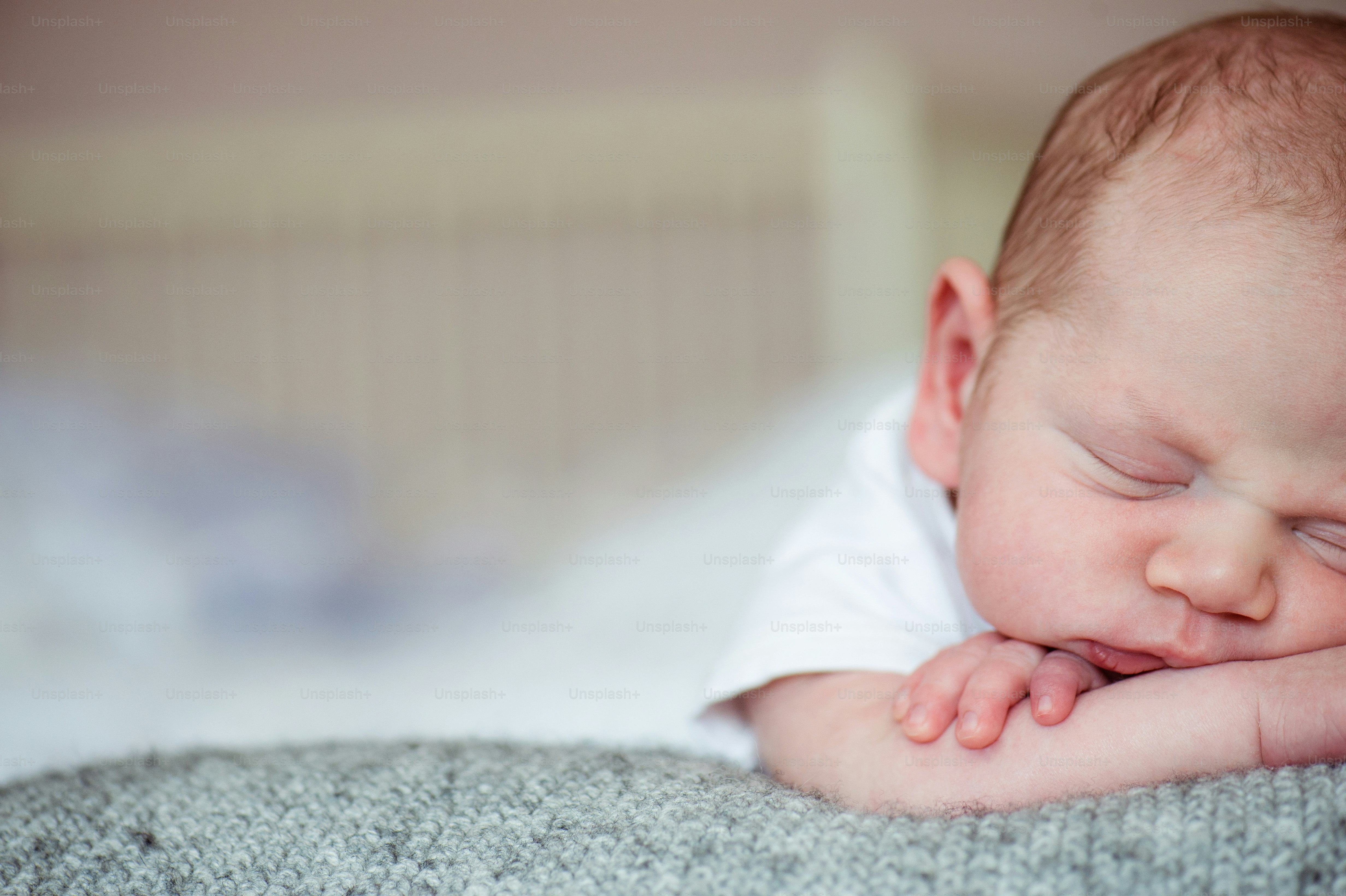 Cute little newborn baby boy lying on bed, sleeping, close up