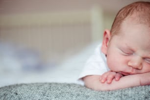 Menino recém-nascido pequeno bonito deitado na cama, dormindo, close up