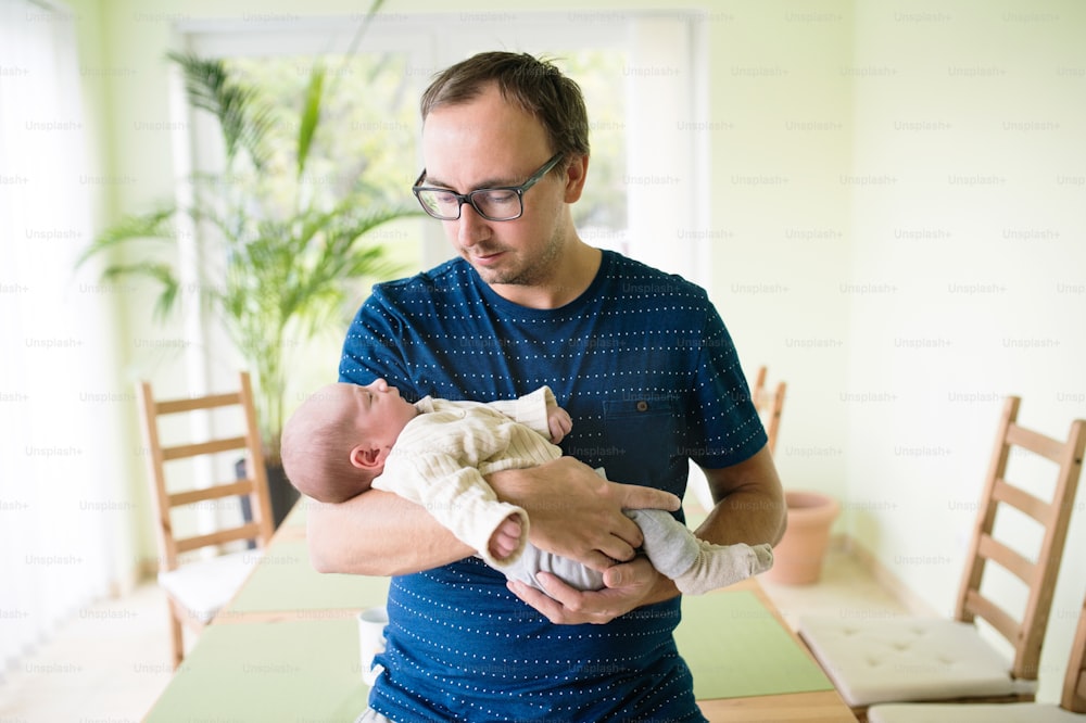Pai jovem segurando seu filho recém-nascido em seus braços em casa