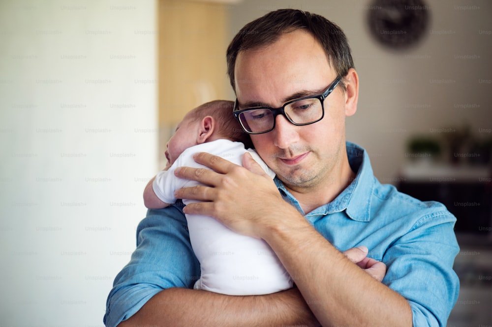 Close up of young father holding his newborn baby son in his arms