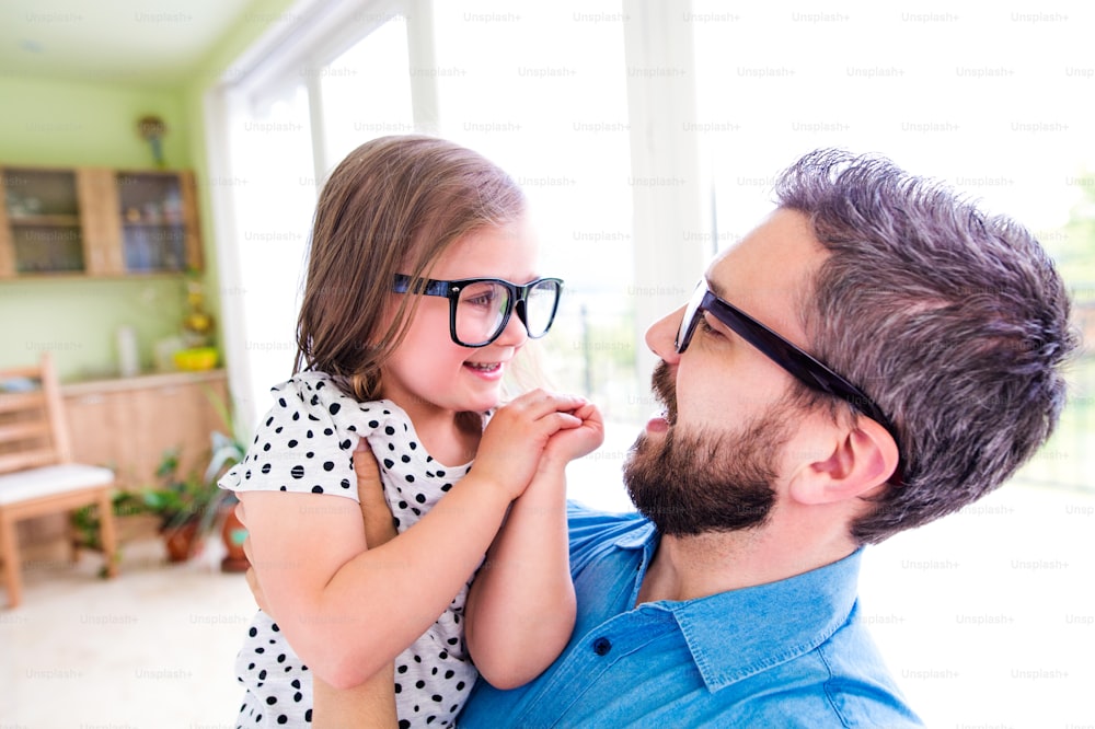 Padre con su pequeña hija con gafas negras hipster, día soleado en el interior