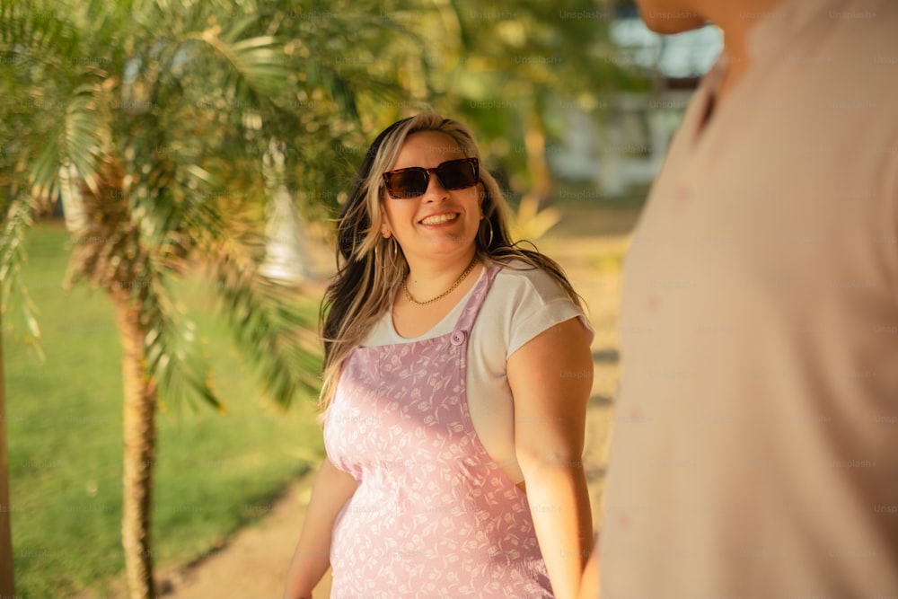 a pregnant woman in a pink dress smiles at a man