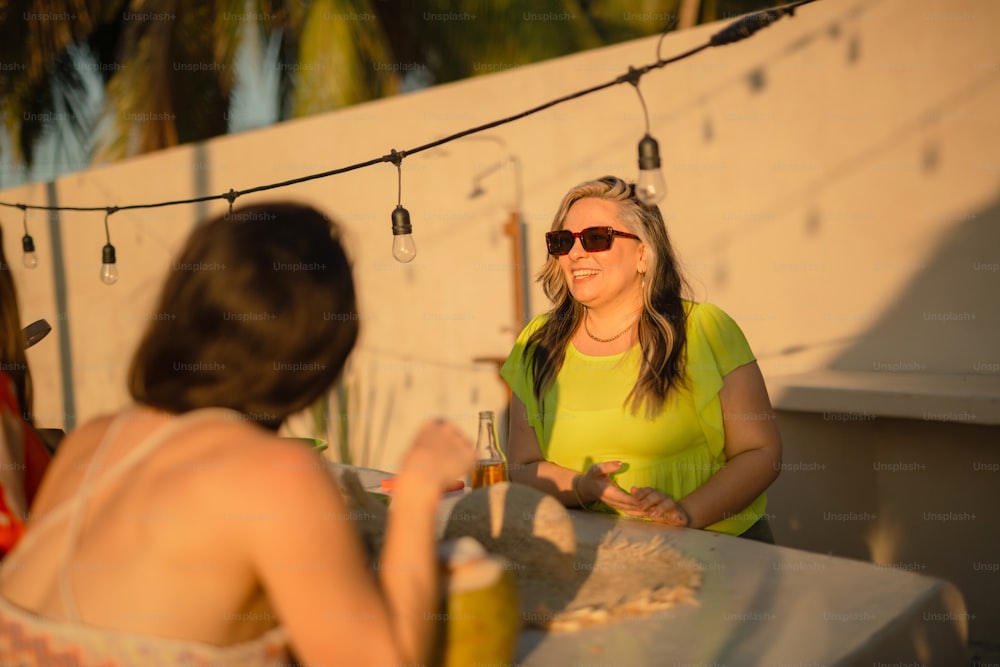 eine Frau, die mit einem Glas Wein an einem Tisch sitzt
