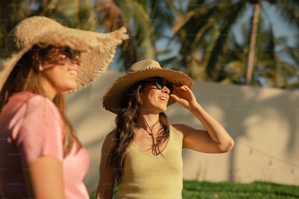a woman wearing a hat and sunglasses standing next to another woman