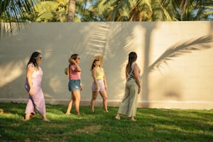 a group of women standing next to a white wall